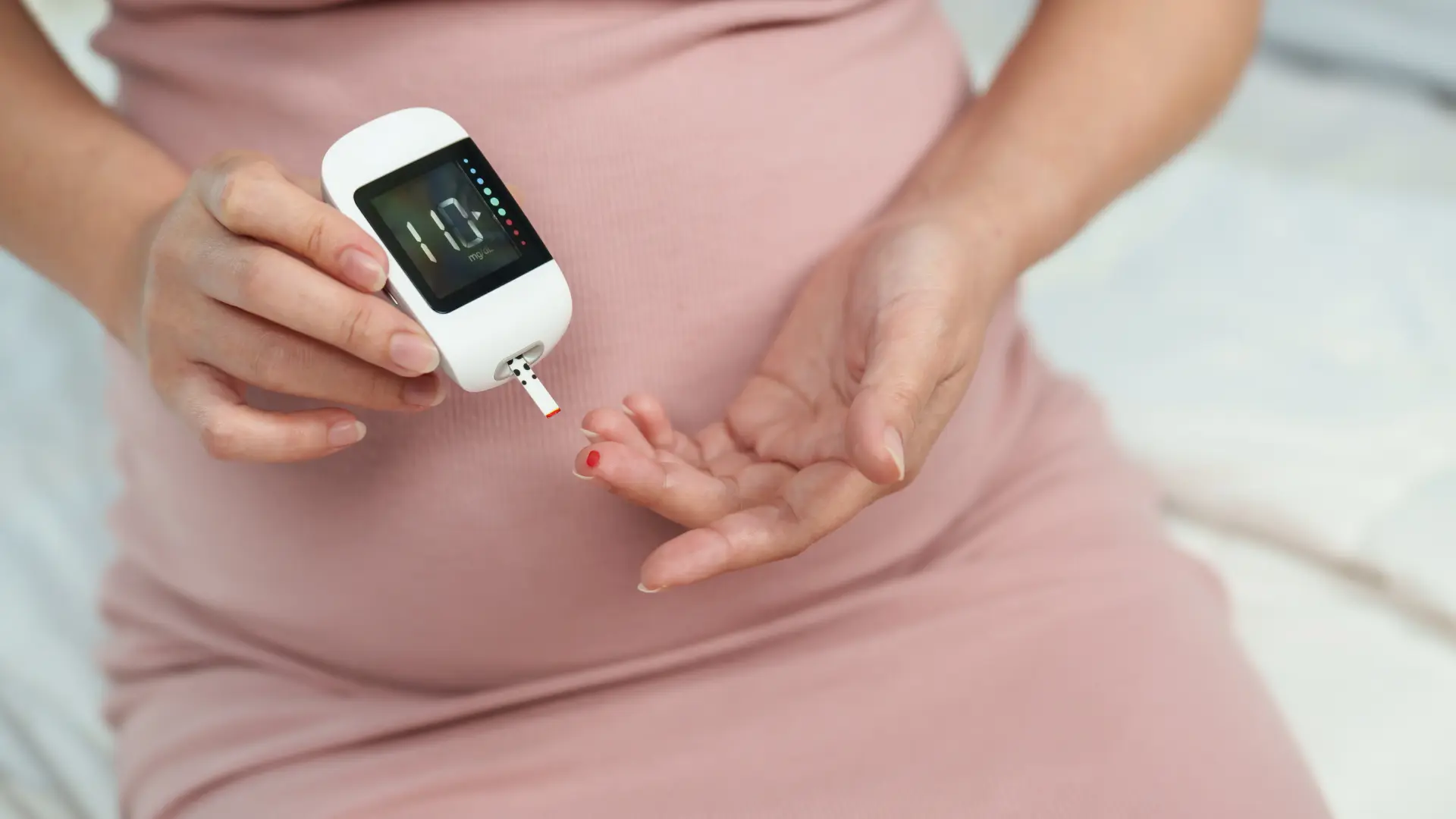 A pregnant woman confidently monitors her blood sugar as part of her high-risk pregnancy care for gestational diabetes.